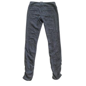 Op de afbeelding: Donkergrijze tweed broek met hoge taille en een getailleerde pasvorm. De broek heeft een knoop- en ritssluiting, riemlussen en zakken. De pijpen lopen taps toe naar een geplooid detail bij de enkels.