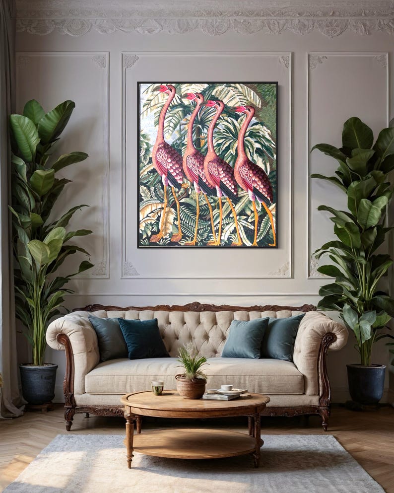 Puede incluir: Un sof&aacute; beige capiton&eacute; con cuatro almohadas, dos de color turquesa y dos de color verde oscuro, se encuentra frente a una impresi&oacute;n enmarcada de cinco flamencos rosas en un entorno de jungla tropical. Una mesa de centro redonda de madera con un estante inferior se encuentra frente al sof&aacute;. Dos plantas grandes en macetas con hojas verdes se encuentran a ambos lados del sof&aacute;.