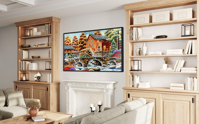 Puede incluir: Una pintura enmarcada que representa una escena r&uacute;stica con una casa de madera, una rueda de agua y un puente de piedra sobre un arroyo. La pintura est&aacute; ambientada en un fondo de &aacute;rboles y cielo azul.
