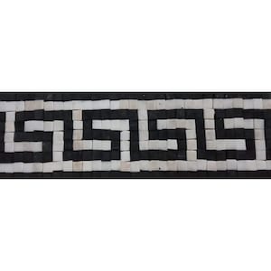 Puede incluir: Borde de mosaico de azulejos negros y blancos con un patrón de clave griega. Los azulejos son cuadrados pequeños dispuestos en un diseño repetitivo.