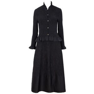 May include: A black long-sleeved dress with a textured, crinkled fabric finish. The bodice features a button-down front, a ruffled stand collar, and a peplum waist. The sleeves have ruffled cuffs, and the skirt falls to a midi length with a pleated hem.