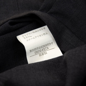 May include: Close-up of a black fabric with a white tag attached. The tag has Japanese text and the words "Made in Japan". The fabric is folded, showing its texture and the tag's details.
