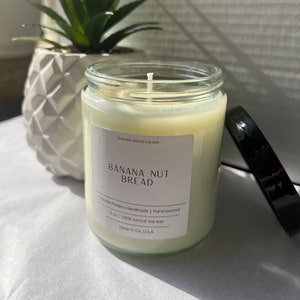 May include: A clear glass candle jar with a white label that reads "Scented natural soy wax", "BANANA NUT BREAD", "Celestial Flowers Handmade | Hand poured", "8 oz | 100% natural soy wax", and "Made in CA, USA".