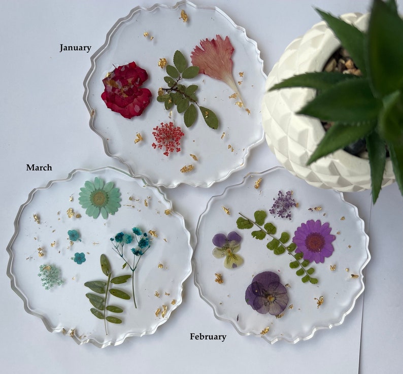 May include: Three round resin coasters with pressed flowers and gold leaf. The coasters are labeled "January", "February", and "March".