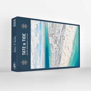 May include: A navy blue box containing a 500-piece jigsaw puzzle, titled "Tate & Tide." The puzzle depicts a coastal scene with a beach, buildings, and ocean in blue, white, and beige. The box also displays the puzzle title and piece count.