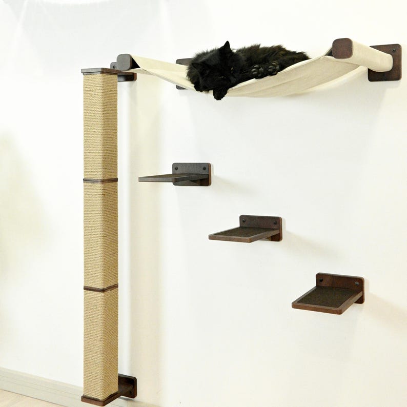 May include: A wall-mounted cat tree with a beige hammock, three dark brown shelves, and a sisal scratching post. A black cat is resting in the hammock. The cat tree is designed for feline enrichment and relaxation.