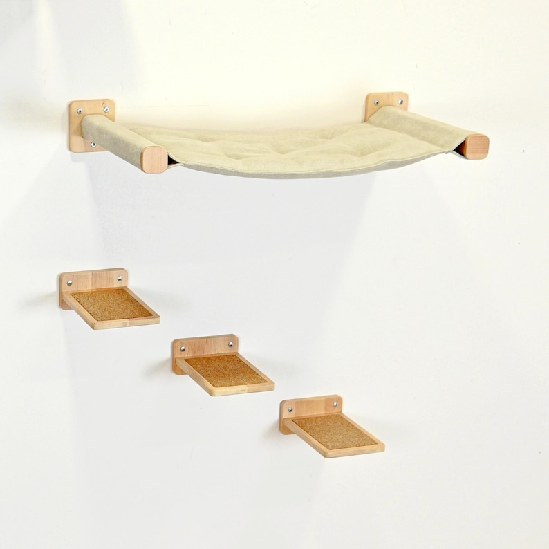 May include: A wall-mounted cat furniture set featuring a beige hammock and three wooden steps. The hammock is suspended between wooden supports, and the steps have a cork surface. The set is designed for feline climbing and lounging.