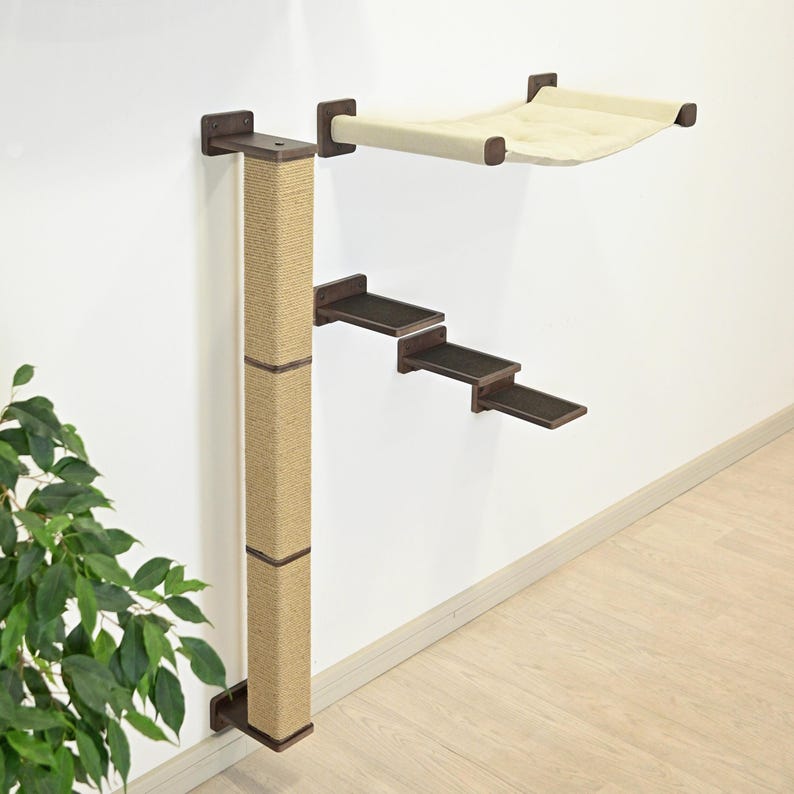 May include: A wall-mounted cat tree with a sisal scratching post, three dark brown steps, and a beige hammock. The cat furniture is attached to a white wall with dark brown brackets.
