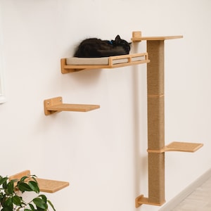 May include: A wall-mounted cat tree with multiple platforms and a scratching post. The cat tree is made of wood and has a natural finish. A black cat is sleeping on one of the platforms.