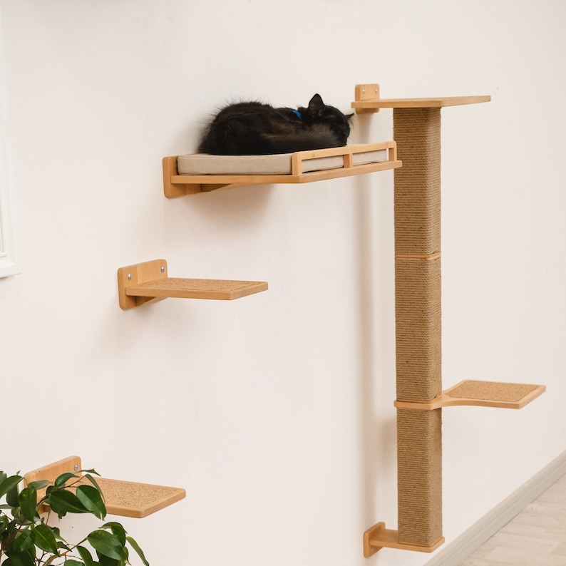 May include: A wall-mounted cat tree with multiple platforms and a scratching post. The cat tree is made of wood and has a natural finish. A black cat is sleeping on one of the platforms.