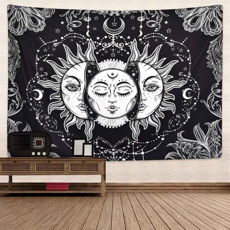May include: Black and white tapestry featuring a stylized sun with two faces, surrounded by stars and floral designs.