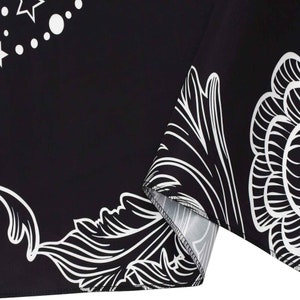 May include: Black fabric with a white floral pattern. The fabric has a white border and a white seam.