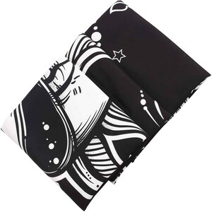 May include: Black and white tapestry with a mandala design featuring a large eye and intricate patterns. The tapestry is folded in half.