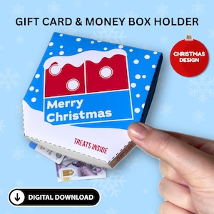 Peut inclure: Boîte cadeau et porte-monnaie sur le thème de Noël. La boîte est bleue avec des flocons de neige blancs et un motif rouge et blanc. Les mots "Merry Christmas" sont imprimés sur le devant. La boîte est ouverte, révélant de l'argent.
