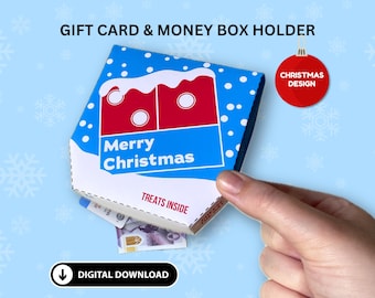 Puede incluir: Un portatarjetas y caja de dinero con temática navideña. La caja es azul con copos de nieve blancos y un diseño rojo y blanco. Las palabras "Merry Christmas" están impresas en la parte delantera. La caja está abierta, revelando dinero.