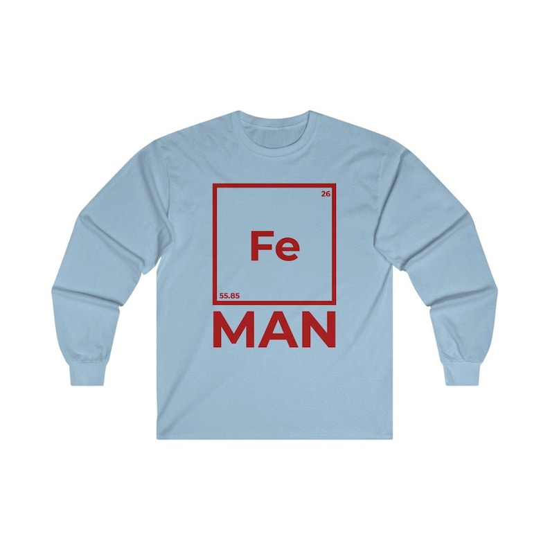 Puede incluir: Una camiseta de manga larga azul claro con un gr&aacute;fico cuadrado rojo que presenta el s&iacute;mbolo qu&iacute;mico "Fe" para el hierro, el n&uacute;mero at&oacute;mico "26" y el peso at&oacute;mico "55,85". La palabra "MAN" est&aacute; impresa debajo del cuadrado.