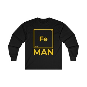 Puede incluir: Camiseta negra de manga larga con un gr&aacute;fico amarillo del elemento hierro de la tabla peri&oacute;dica, Fe, con el texto "MAN" debajo.