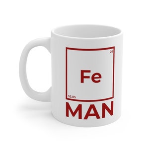 Può includere: Tazza in ceramica bianca con una grafica quadrata rossa che presenta il simbolo chimico "Fe" per il ferro, il numero atomico "26" e il peso atomico "55,85". Il testo "MAN" è stampato sotto il quadrato.