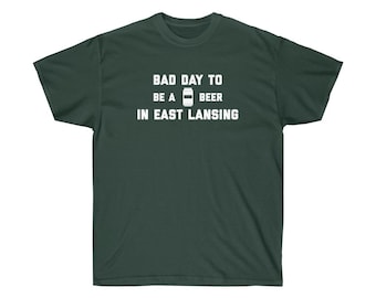 Puede incluir: Una camiseta verde oscuro con texto blanco que dice "Mal día para ser una cerveza en East Lansing".
