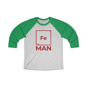 May include: A gray and green baseball tee shirt with a red square graphic featuring the chemical symbol for iron, Fe, and the word "MAN" below it.