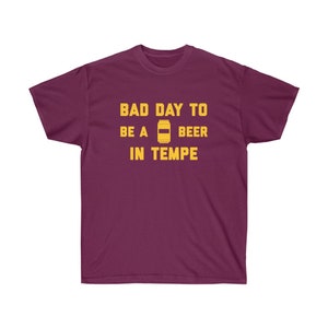 May include: A maroon t-shirt with the text "Bad Day To Be A Beer In Tempe" in yellow lettering. A yellow beer can icon is between the words "Be A" and "Beer".