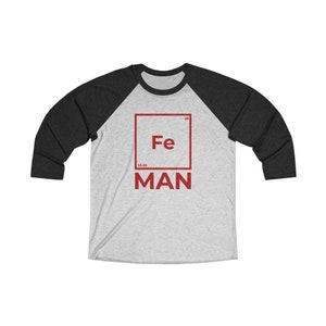 May include: A grey and black baseball tee shirt with a red square graphic featuring the chemical symbol for iron, Fe, and the word "MAN" below it.