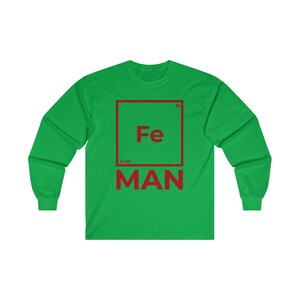Puede incluir: Camiseta de manga larga verde con un gr&aacute;fico cuadrado rojo que presenta el s&iacute;mbolo qu&iacute;mico "Fe" para el hierro, el n&uacute;mero at&oacute;mico "26" y el peso at&oacute;mico "55,85". El texto "MAN" est&aacute; debajo del cuadrado.