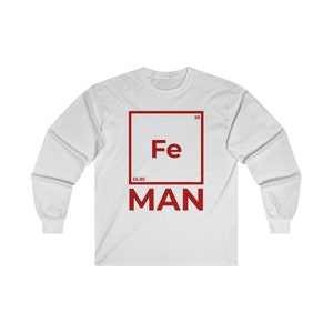 Puede incluir: Camiseta blanca de manga larga con un gr&aacute;fico cuadrado rojo que presenta el s&iacute;mbolo qu&iacute;mico "Fe" para el hierro, el n&uacute;mero at&oacute;mico "26" y el peso at&oacute;mico "55,85". La palabra "MAN" est&aacute; impresa debajo del cuadrado.