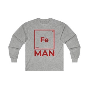 Puede incluir: Una camiseta de manga larga gris con un gr&aacute;fico cuadrado rojo que presenta el s&iacute;mbolo qu&iacute;mico "Fe" para el hierro, el n&uacute;mero at&oacute;mico "26" y el peso at&oacute;mico "55,85". El texto "MAN" est&aacute; impreso debajo del cuadrado.