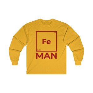 Puede incluir: Una camiseta amarilla de manga larga con un gr&aacute;fico cuadrado rojo que presenta el s&iacute;mbolo qu&iacute;mico "Fe" para el hierro, el n&uacute;mero at&oacute;mico "26" y el peso at&oacute;mico "55,85". El texto "MAN" est&aacute; debajo del cuadrado.