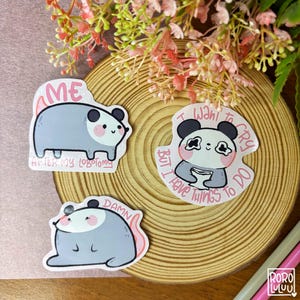 Peut inclure: Trois autocollants découpés représentant des animaux de dessins animés. L'un montre un opossum gris avec le texte "ME AFTER MY LOBOTOMY". Un autre montre un panda avec le texte "I WANT TO CRY BUT I HAVE THINGS TO DO". Le troisième montre un opossum gris avec le texte "DAMN".