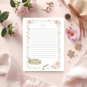 Peut inclure: Un bloc-notes blanc avec des pages lignées, orné d'une bordure florale de roses roses et de feuilles vertes. Le mot "Notes" est en haut. Une illustration à l'aquarelle d'un bâtiment est en bas. Le bloc-notes est entouré de fleurs et d'accessoires.