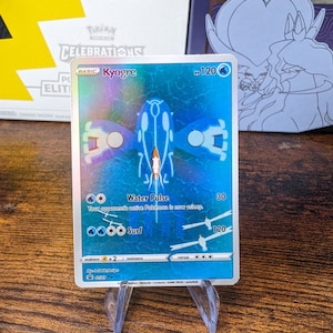 Könnte beinhalten: Eine holografische Pokemon-Sammelkarte mit Kyogre, einem Wasser-Pokemon. Die Karte ist blau und zeigt ein Bild von Kyogre mit seinen charakteristischen Attacken Wasserpuls und Surfer. Die Karte hat 120 KP.