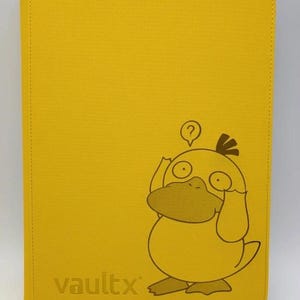 May include: Yellow card binder featuring a Psyduck cartoon illustration. The binder has the word "vaultx" printed on the lower left. The Psyduck character is depicted in a thinking pose with a question mark above its head.