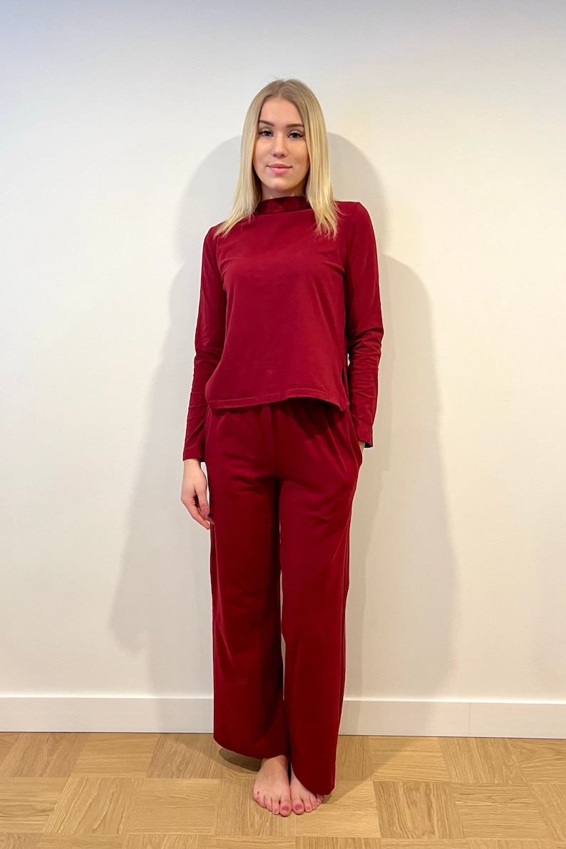 Pu&ograve; includere: Un completo da salotto bordeaux composto da due pezzi. Il set comprende un top a maniche lunghe con collo alto e pantaloni a gamba larga. L'outfit &egrave; realizzato in un materiale morbido e confortevole.