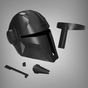 May include: A black plastic helmet with a visor and a round, circular detail on the side. The helmet is disassembled into multiple pieces, including a separate visor and a top piece.