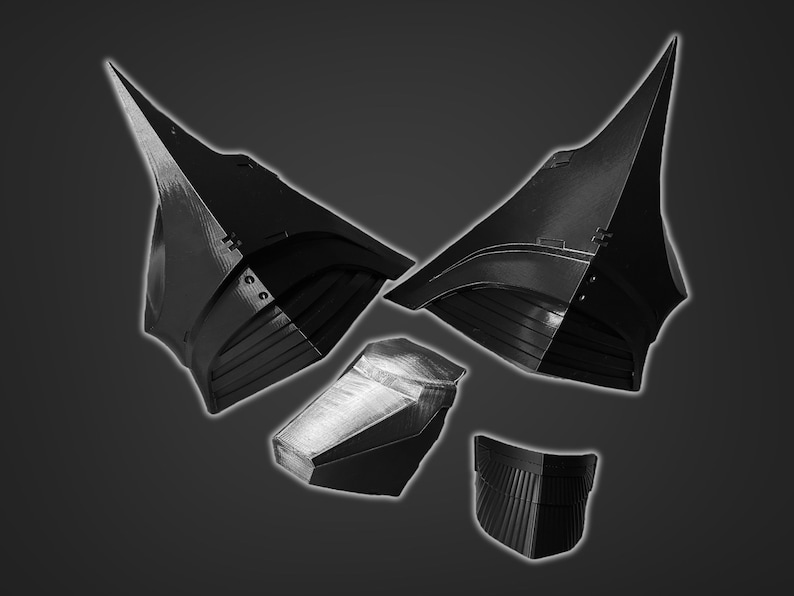 Puede incluir: Un conjunto de cinco piezas de casco impresas en 3D en negro. Las piezas tienen forma de casco con una parte superior puntiaguda y una parte inferior curva. Las piezas est&aacute;n dise&ntilde;adas para ensamblarse y crear un casco completo.