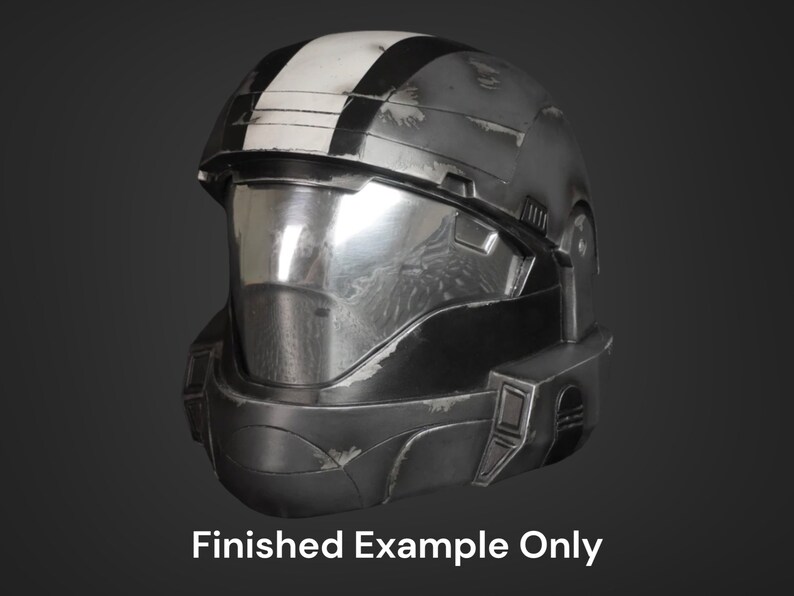 Puede incluir: Un casco negro y plateado con una franja blanca en la parte superior. El casco tiene una visera y un aspecto desgastado.