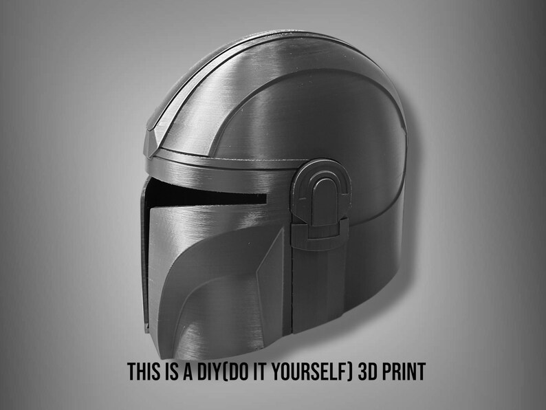 Puede incluir: Un casco negro y gris impreso en 3D, con visera y parte superior redondeada. El texto "THIS IS A DIY(DO IT YOURSELF) 3D PRINT" est&aacute; en la parte inferior. El casco tiene apariencia met&aacute;lica, probablemente un accesorio o disfraz.