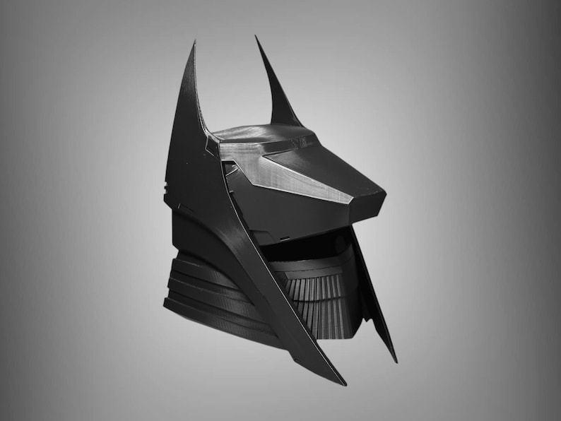 Puede incluir: Un casco negro impreso en 3D con un dise&ntilde;o angular y puntiagudo. El casco tiene una barbilla puntiaguda y alargada y dos orejas altas y puntiagudas.