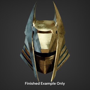 Puede incluir: Un casco dorado y azul con un dise&ntilde;o afilado y angular. El casco tiene una parte superior puntiaguda y una m&aacute;scara facial.