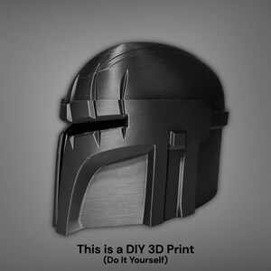Puede incluir: Un casco negro impreso en 3D, probablemente para cosplay o exhibici&oacute;n. El casco tiene un dise&ntilde;o detallado con formas angulares y una zona de visera. El texto en la parte inferior dice: "This is a DIY 3D Print (Do It Yourself)".