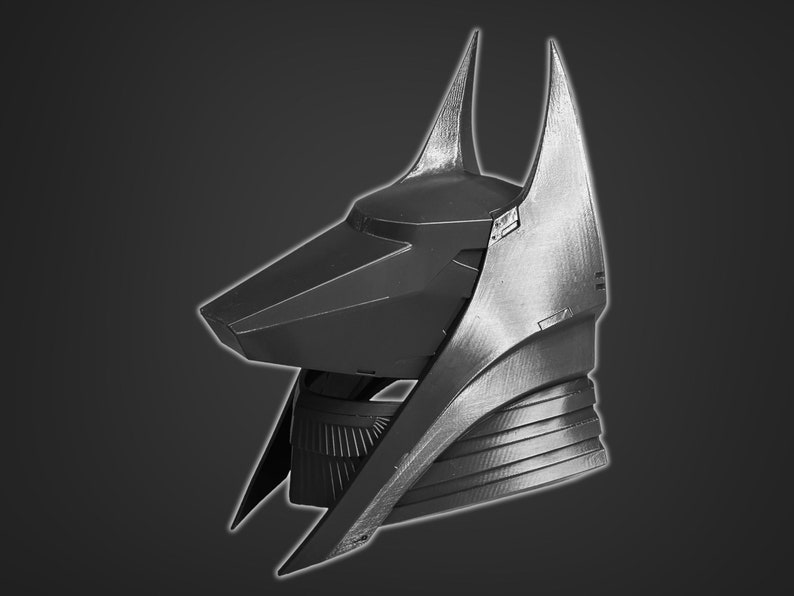 Puede incluir: Un casco negro y plateado con un dise&ntilde;o puntiagudo y angular. El casco tiene una forma alargada distintiva con una parte superior puntiaguda y una l&iacute;nea de la mand&iacute;bula afilada y angular.