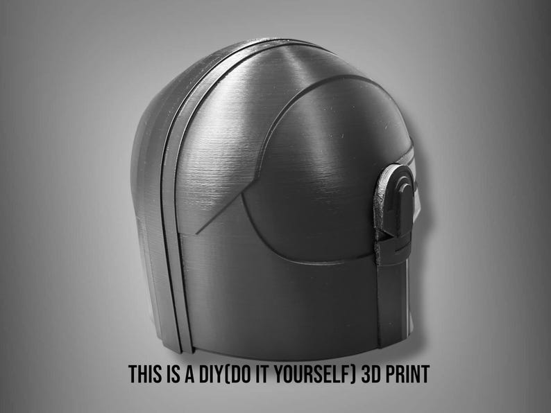 Puede incluir: Un casco negro y gris impreso en 3D con una superficie texturizada. El casco tiene una parte superior redondeada y un detalle tipo visera en el lateral. El texto en la parte inferior dice "THIS IS A DIY(DO IT YOURSELF) 3D PRINT."
