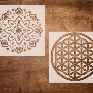 May include: Two white stencils with intricate mandala designs. The first stencil features a circular mandala with a flower-like pattern. The second stencil features a circular mandala with a geometric pattern.