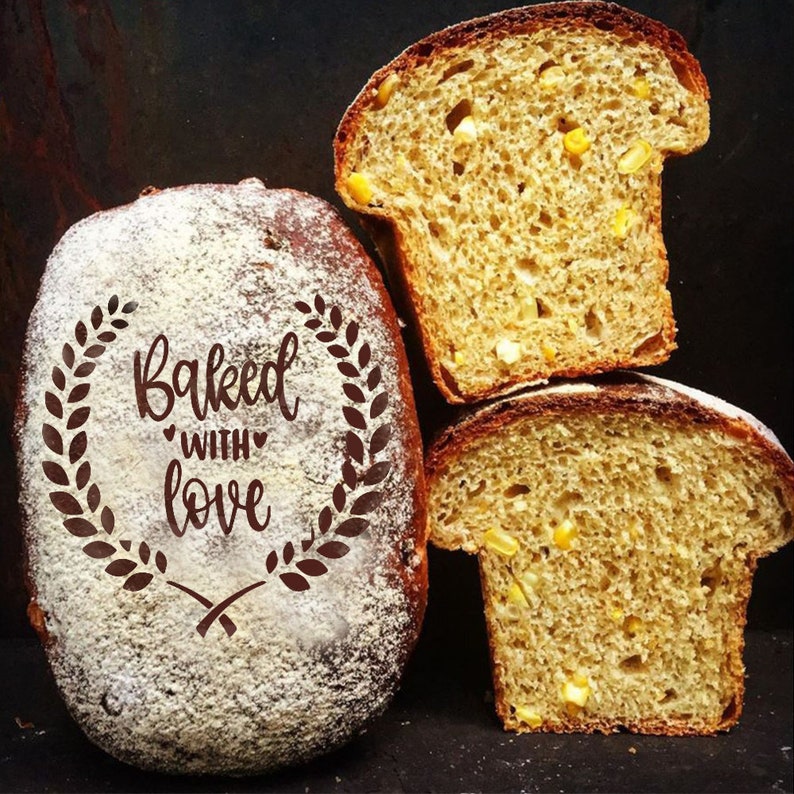 May include: Three slices of freshly baked cornbread. The loaf on the left is dusted with powdered sugar and has the words "Baked with love" written on it.