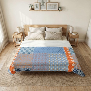 May include: A patchwork quilt with a Japanese-inspired design. The quilt features various blue, orange, and white floral and geometric patterns. The quilt is on a bed with a wooden headboard and nightstands.
