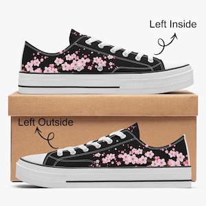 Könnte beinhalten: Schwarze Leinenschuhe mit weißer Sohle und Schnürsenkeln. Die Schuhe haben ein rosa Blumenmuster. Die Schuhe werden auf einem Karton präsentiert. Der Text "Left Inside" und "Left Outside" sind sichtbar.