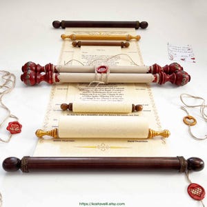 Può includere: Diversi rotoli decorativi con manici in legno e carta arrotolata. I rotoli variano per dimensioni e colore, alcuni con dettagli rossi e dorati. Un rotolo è sigillato con cera rossa e legato con spago. Sfondo chiaro.