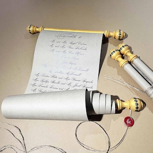 May include: A set of light gray paper scrolls with black calligraphy text, featuring wooden rods with gold-painted ends and dark decorative studs. One scroll is unrolled to reveal a guest list, while others remain rolled with a red wax seal attached.